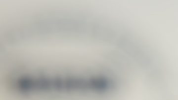 Moneda de 25 centavos de dólar estadounidense sostenida con los dedos sobre un fondo con el logotipo de USAID.