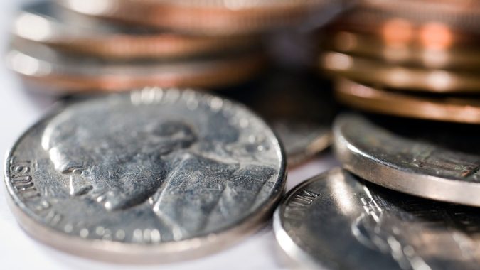 Una vista de cerca de varias monedas estadounidenses, incluida una de cinco centavos con la imagen de Jefferson, con monedas de un centavo y de diez centavos apiladas cerca.