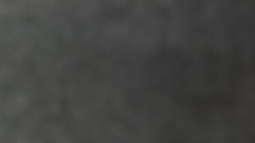 Billetes de dólar en un carrito de supermercado en miniatura sobre una superficie de madera sobre un fondo oscuro.