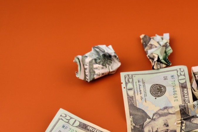 Una pila de billetes de dólar arrugados y sucios sobre una mesa naranja. Concepto de dinero sucio.