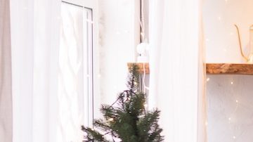 Interior de la sala de estar de estilo escandinavo, decorada para las fiestas navideñas. Árbol de Navidad junto a la chimenea.