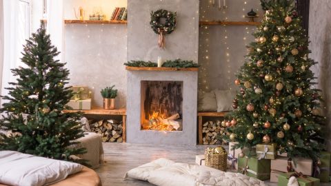 Interior de la sala de estar de estilo escandinavo, decorada para las fiestas navideñas. Árbol de Navidad junto a la chimenea.