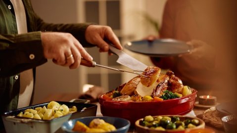 Primer plano de un hombre cortando un pavo asado durante la cena de Acción de Gracias en el comedor.