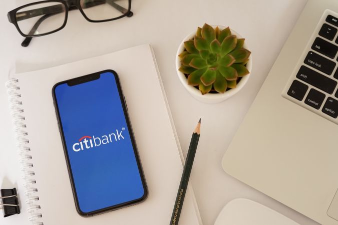 Pantalla de iPhone de Citibank con artículos de papelería y gafas.